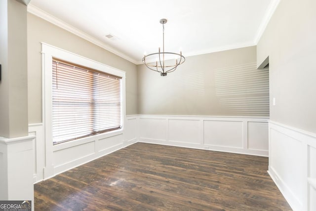 unfurnished dining area featuring dark wood-style floors, a wainscoted wall, crown molding, visible vents, and a chandelier