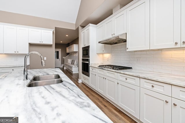 kitchen with light stone countertops, white cabinetry, sink, and stainless steel appliances