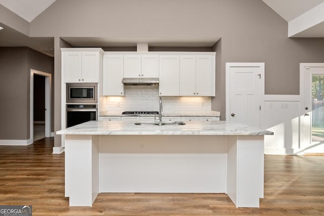 kitchen featuring white cabinets, stainless steel appliances, and an island with sink