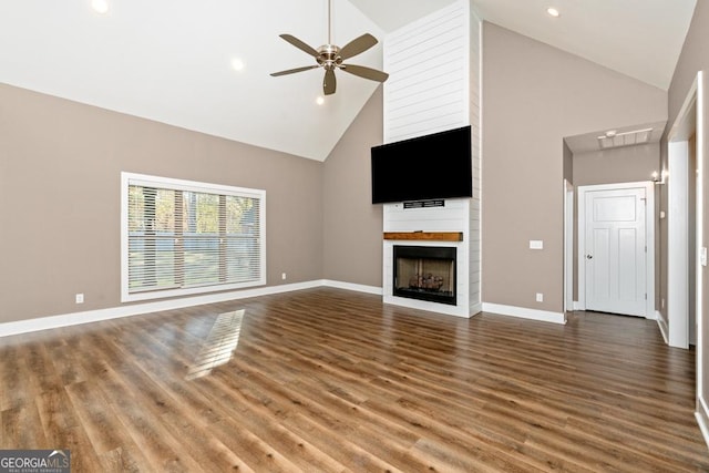 unfurnished living room with hardwood / wood-style floors, ceiling fan, a large fireplace, and high vaulted ceiling