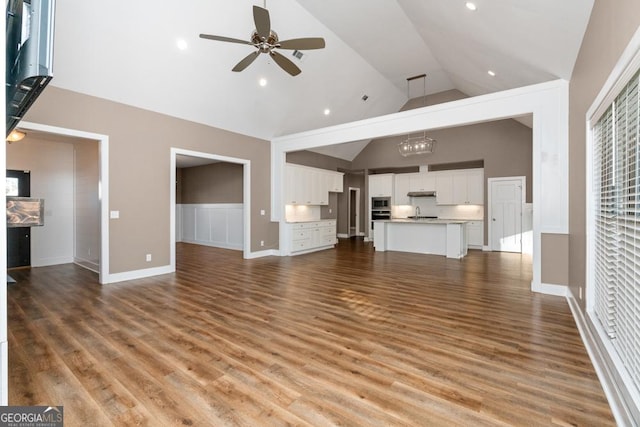 unfurnished living room with hardwood / wood-style flooring, high vaulted ceiling, and ceiling fan