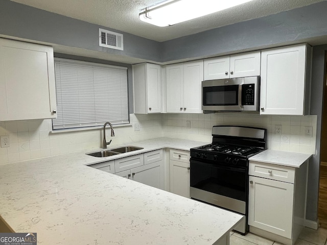 kitchen with backsplash, a textured ceiling, stainless steel appliances, sink, and white cabinetry