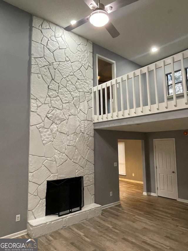 unfurnished living room featuring a stone fireplace, ceiling fan, and hardwood / wood-style floors