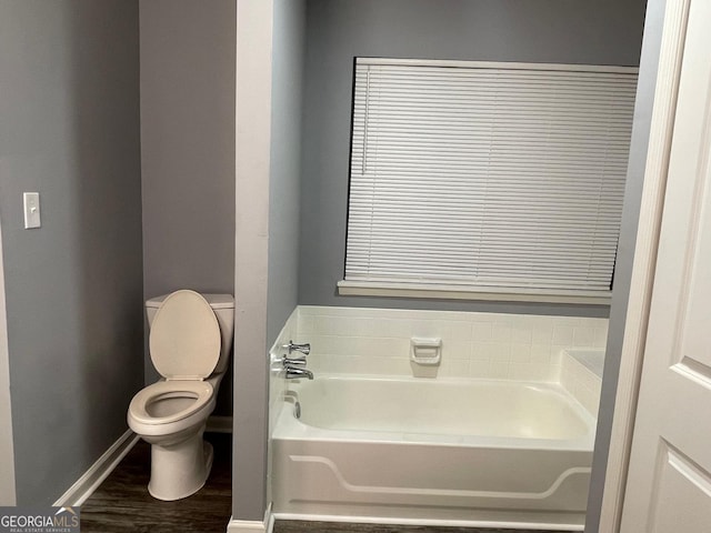 bathroom with hardwood / wood-style floors, a washtub, and toilet