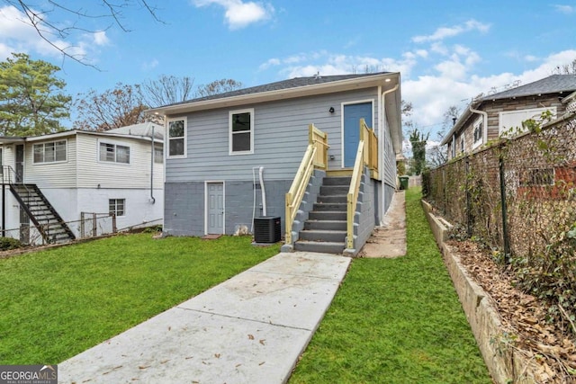 rear view of property featuring a lawn and central AC unit