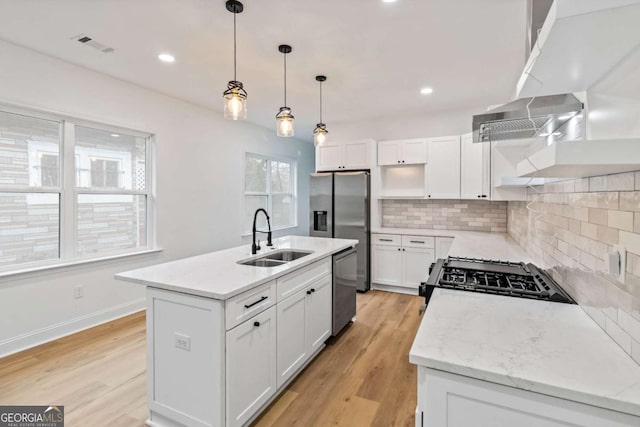 kitchen featuring white cabinetry, sink, a kitchen island with sink, stainless steel appliances, and decorative backsplash