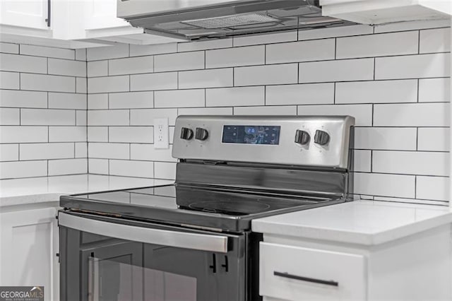 kitchen with white cabinets, decorative backsplash, and stainless steel electric stove