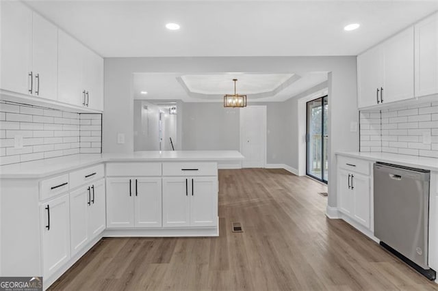 kitchen featuring dishwasher, backsplash, kitchen peninsula, a tray ceiling, and white cabinets