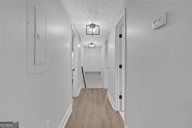 hallway with light hardwood / wood-style floors and a textured ceiling