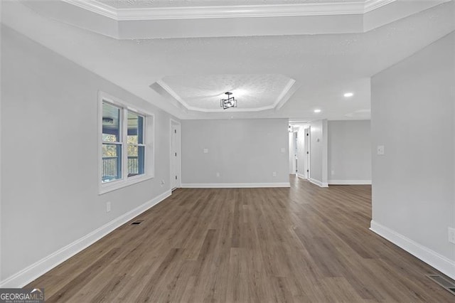 unfurnished living room featuring a textured ceiling, dark hardwood / wood-style flooring, a tray ceiling, and crown molding