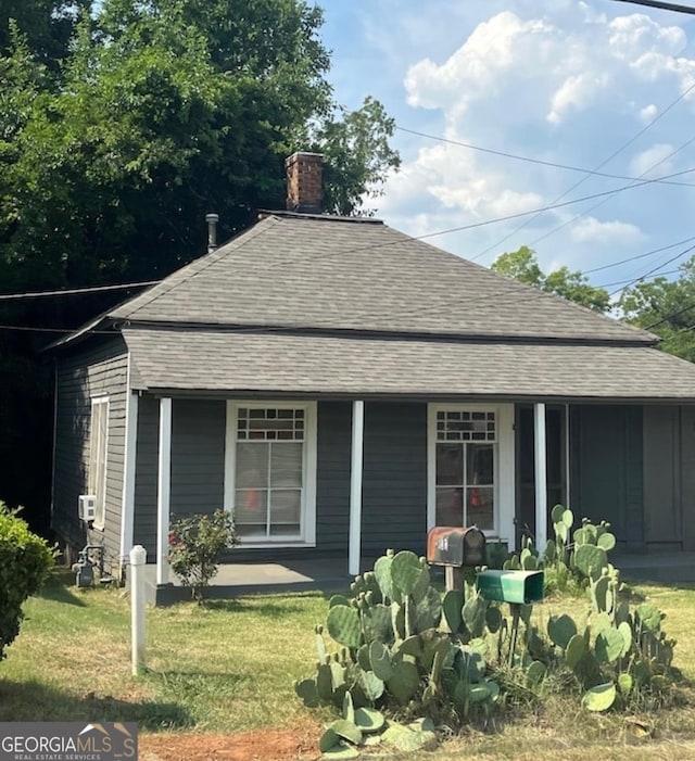 back of property featuring a lawn and covered porch