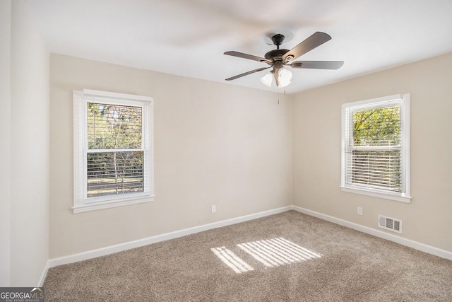 carpeted spare room with a wealth of natural light and ceiling fan