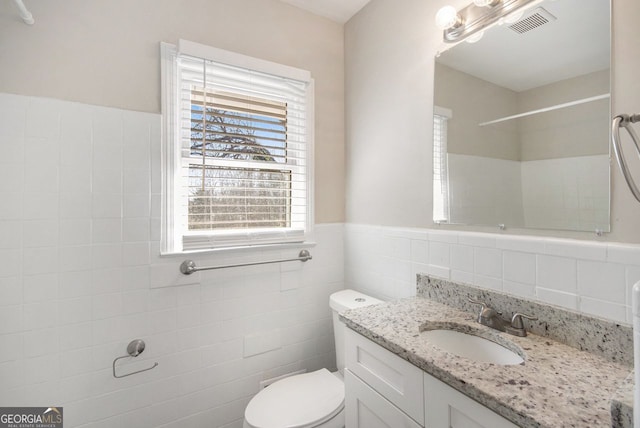 bathroom featuring vanity, tile walls, and toilet