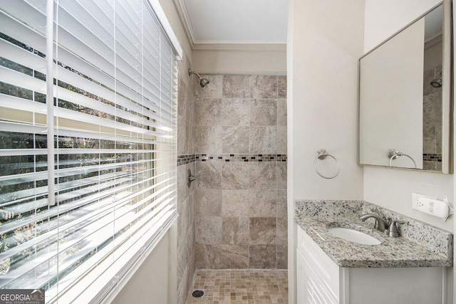 bathroom with vanity, ornamental molding, and tiled shower