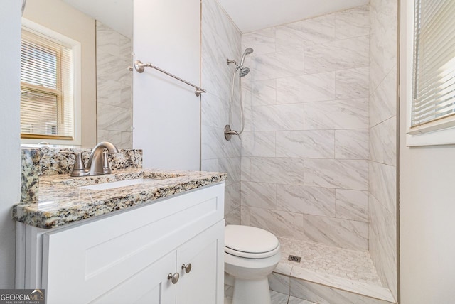 bathroom featuring tiled shower, vanity, and toilet