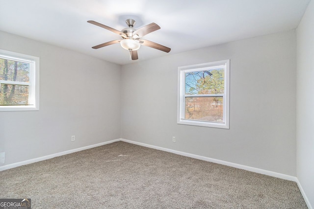 carpeted spare room featuring plenty of natural light and ceiling fan