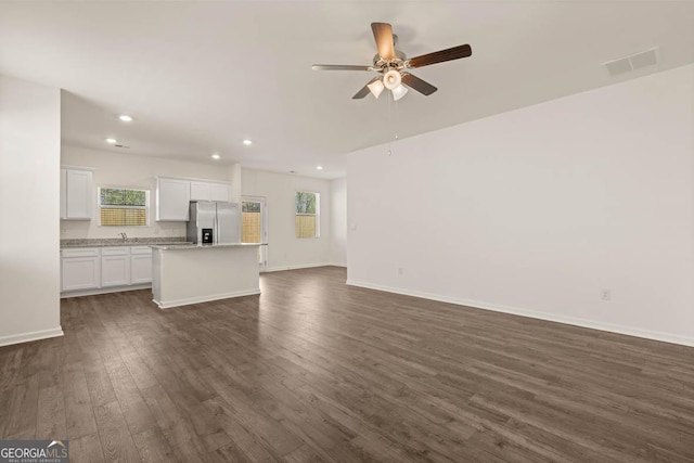 unfurnished living room featuring dark hardwood / wood-style floors, a healthy amount of sunlight, sink, and ceiling fan