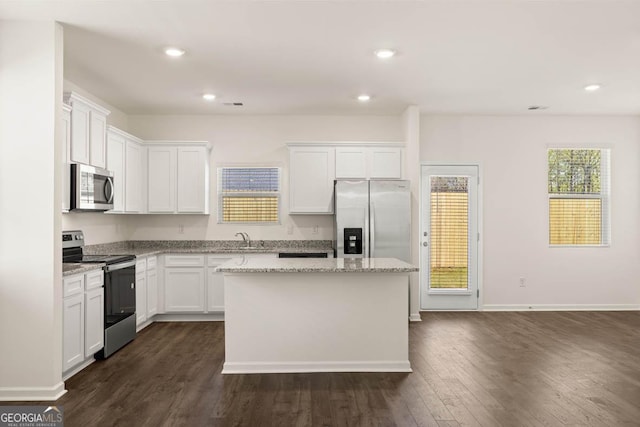 kitchen featuring appliances with stainless steel finishes, a kitchen island, dark wood-type flooring, sink, and white cabinetry