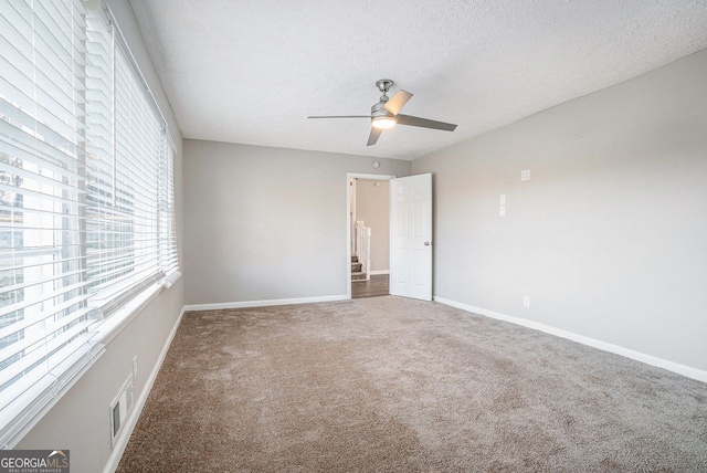 empty room with ceiling fan, carpet floors, and a textured ceiling