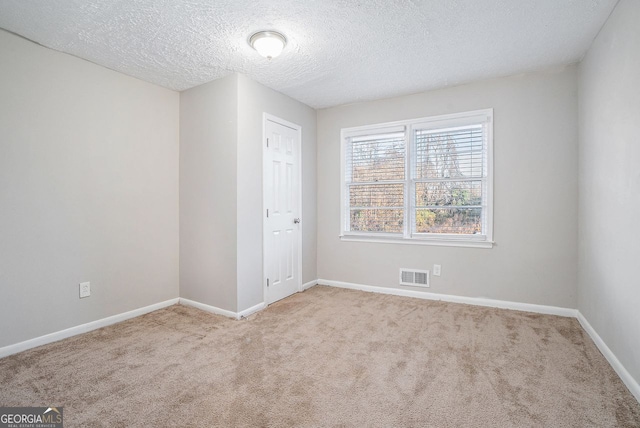 spare room featuring light carpet and a textured ceiling