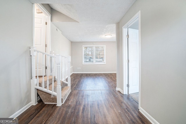 hall with dark hardwood / wood-style flooring and a textured ceiling