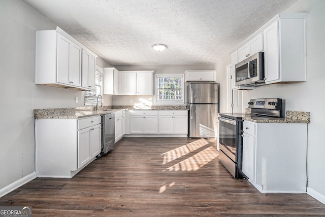 kitchen featuring white cabinetry, light stone countertops, dark hardwood / wood-style floors, a textured ceiling, and appliances with stainless steel finishes