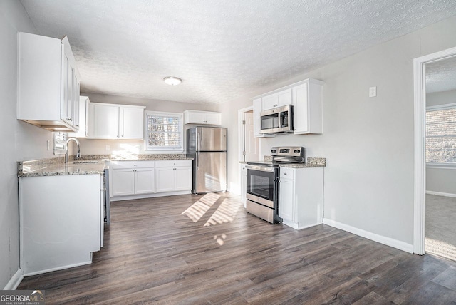 kitchen featuring light stone counters, stainless steel appliances, sink, white cabinets, and dark hardwood / wood-style floors