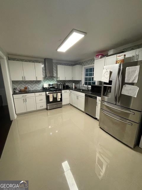 kitchen featuring sink, wall chimney exhaust hood, decorative backsplash, white cabinetry, and stainless steel appliances