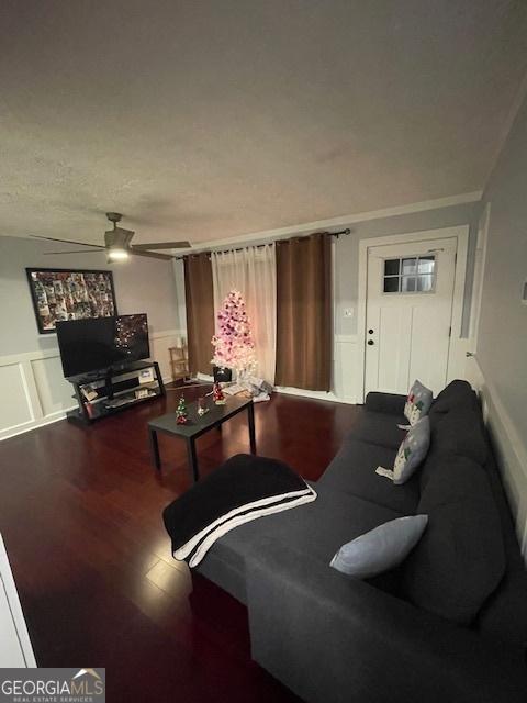 living room featuring ceiling fan, wood-type flooring, and a textured ceiling