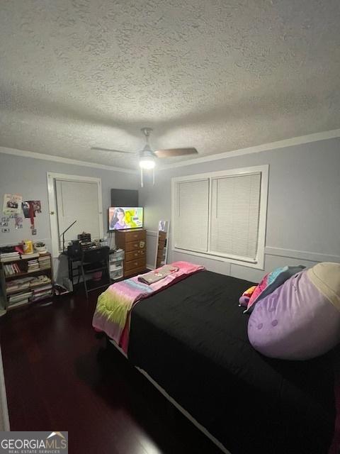 bedroom featuring hardwood / wood-style flooring, ceiling fan, ornamental molding, and a textured ceiling