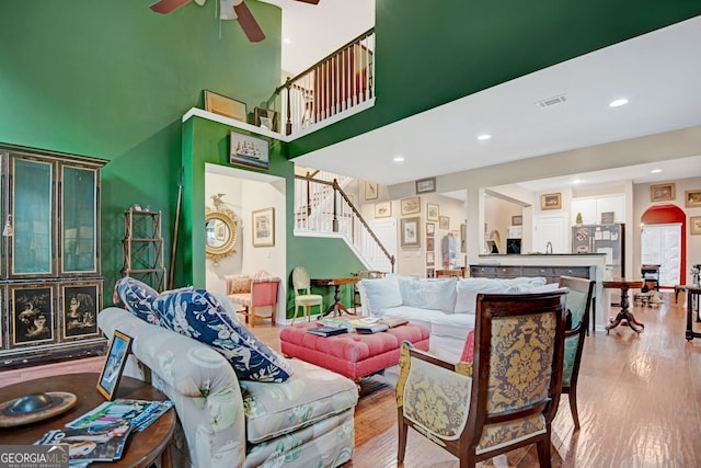 living room with ceiling fan, a high ceiling, and hardwood / wood-style flooring