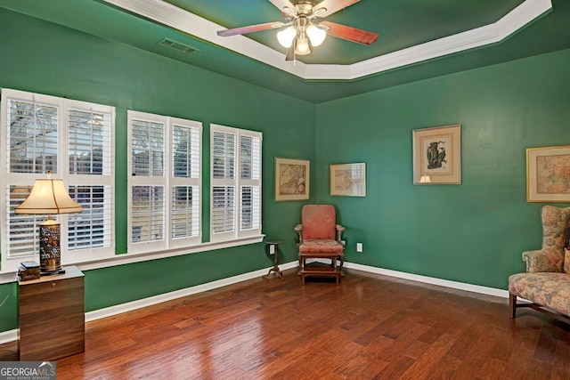 sitting room featuring a raised ceiling, ceiling fan, dark wood-type flooring, and crown molding