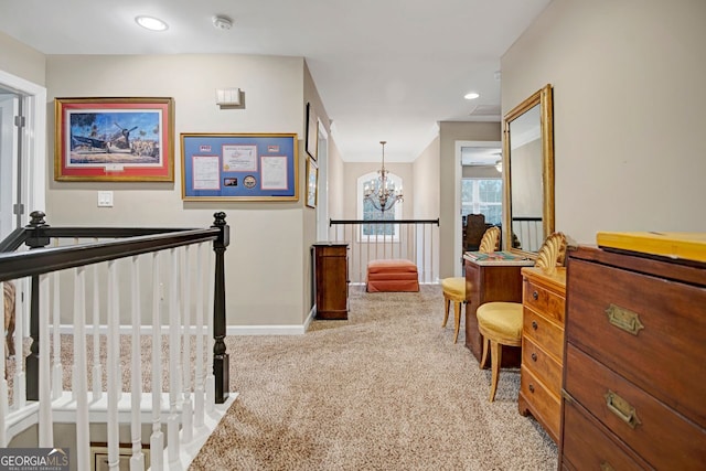 hallway with light colored carpet and a chandelier