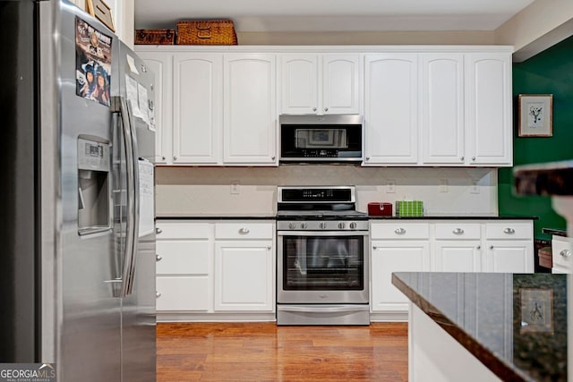 kitchen featuring white cabinets, dark stone countertops, appliances with stainless steel finishes, and tasteful backsplash