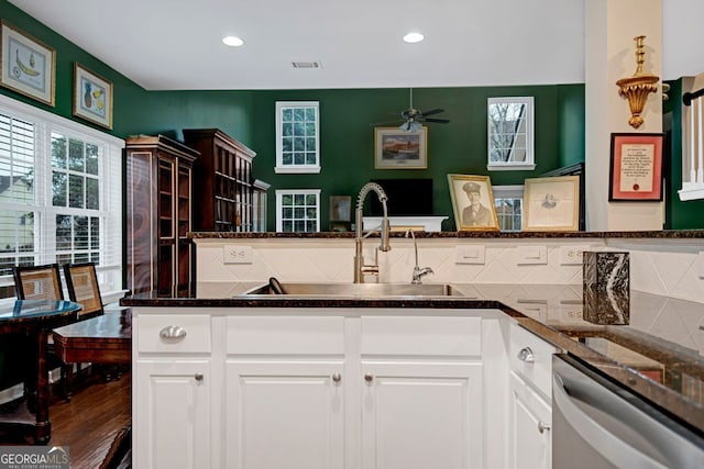 kitchen with dishwasher, dark stone counters, white cabinets, sink, and tasteful backsplash