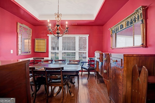 dining space with a tray ceiling, crown molding, hardwood / wood-style floors, and an inviting chandelier