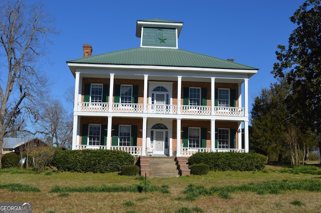 view of front of house featuring a balcony, a front lawn, and covered porch