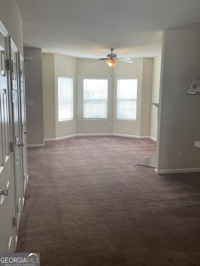 carpeted empty room with ceiling fan and a textured ceiling