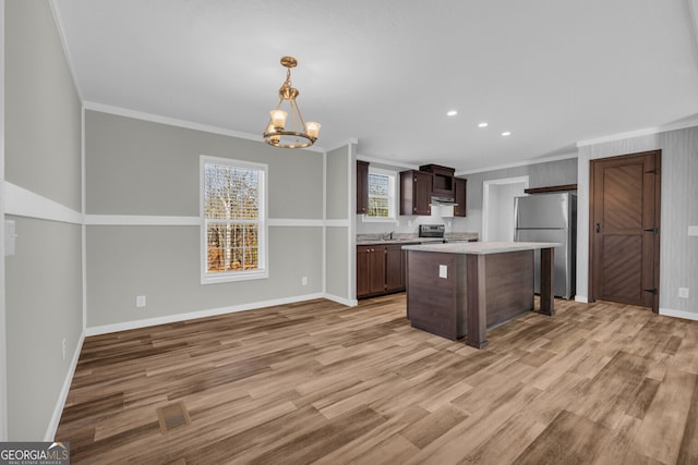 kitchen with an inviting chandelier, hanging light fixtures, crown molding, light wood-type flooring, and appliances with stainless steel finishes