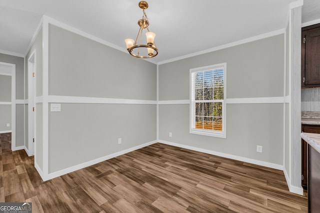 unfurnished dining area with hardwood / wood-style floors, ornamental molding, and a notable chandelier