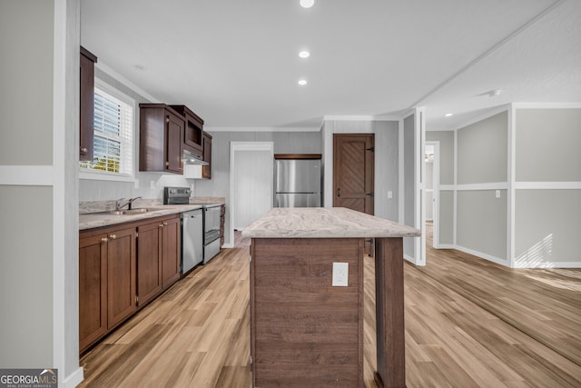 kitchen featuring light hardwood / wood-style floors, a center island, ornamental molding, and appliances with stainless steel finishes