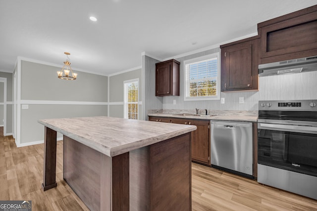 kitchen with pendant lighting, a center island, crown molding, stainless steel appliances, and extractor fan