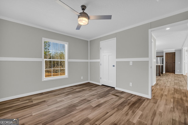 empty room featuring ceiling fan, wood-type flooring, and ornamental molding