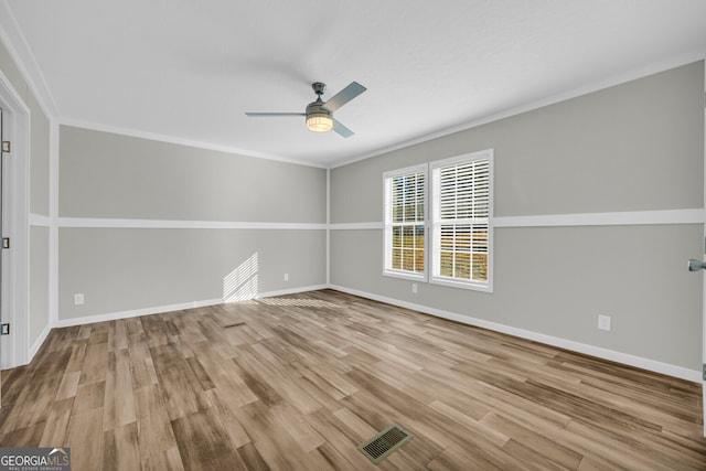 empty room featuring ceiling fan, crown molding, and light wood-type flooring