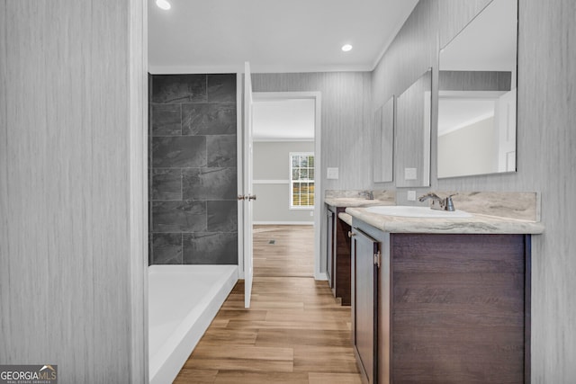 bathroom with crown molding, vanity, and walk in shower