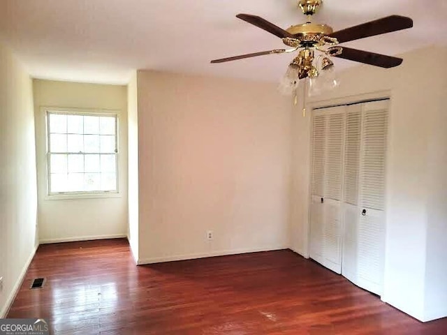 unfurnished bedroom with dark wood-type flooring, a closet, and ceiling fan