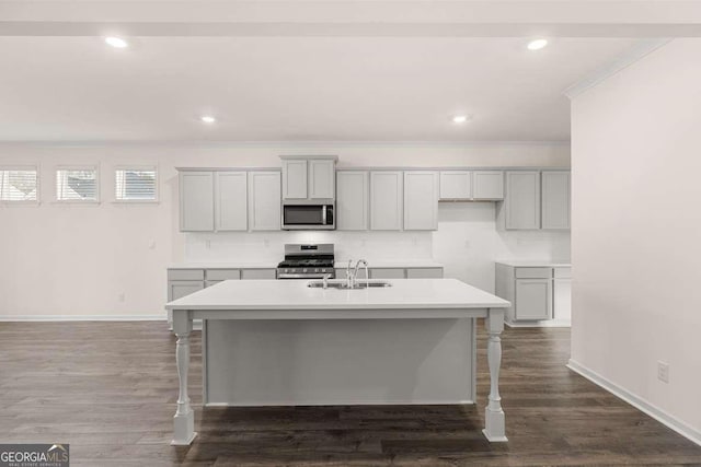 kitchen with stainless steel appliances, sink, gray cabinetry, and an island with sink