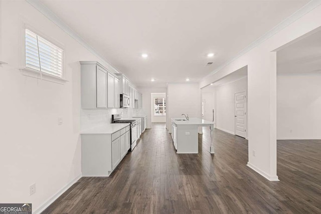 kitchen with stainless steel appliances, sink, an island with sink, a breakfast bar, and crown molding