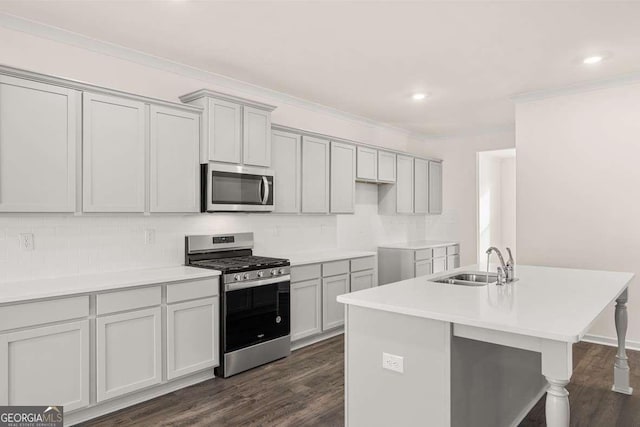 kitchen featuring dark wood-type flooring, stainless steel appliances, a center island with sink, tasteful backsplash, and sink