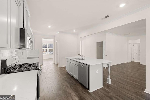 kitchen with a kitchen breakfast bar, a kitchen island with sink, stainless steel appliances, sink, and backsplash